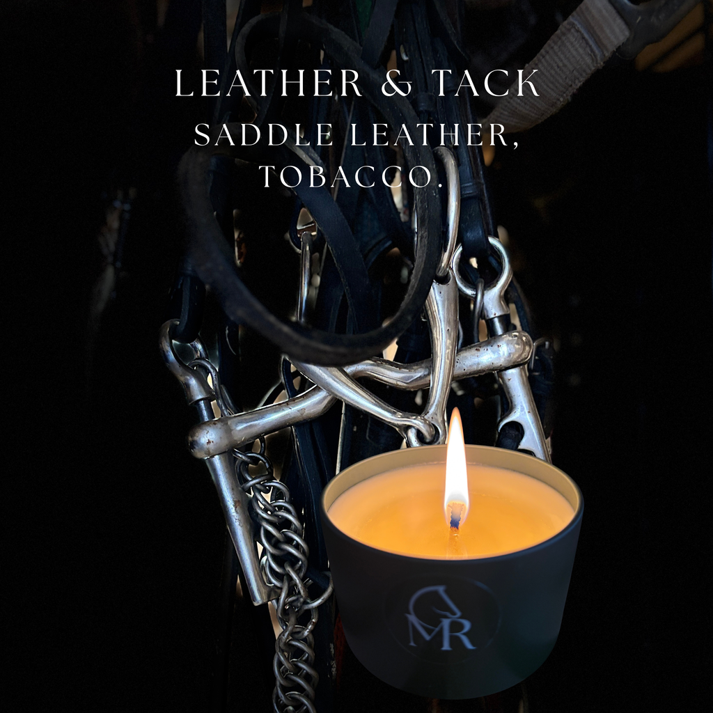 Lit Miss Rio Leather & Tack candle in a dark travel tin, photographed against equestrian bridle and snaffle bit tack on a dark background. Scent notes: bergamot, saddle leather, tobacco, sandalwood.