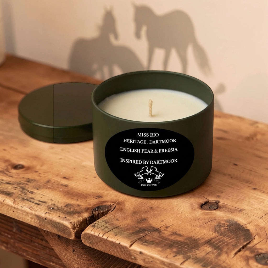 Green luxury soy candle in a tin with a label on a wooden surface, casting a shadow of horses.