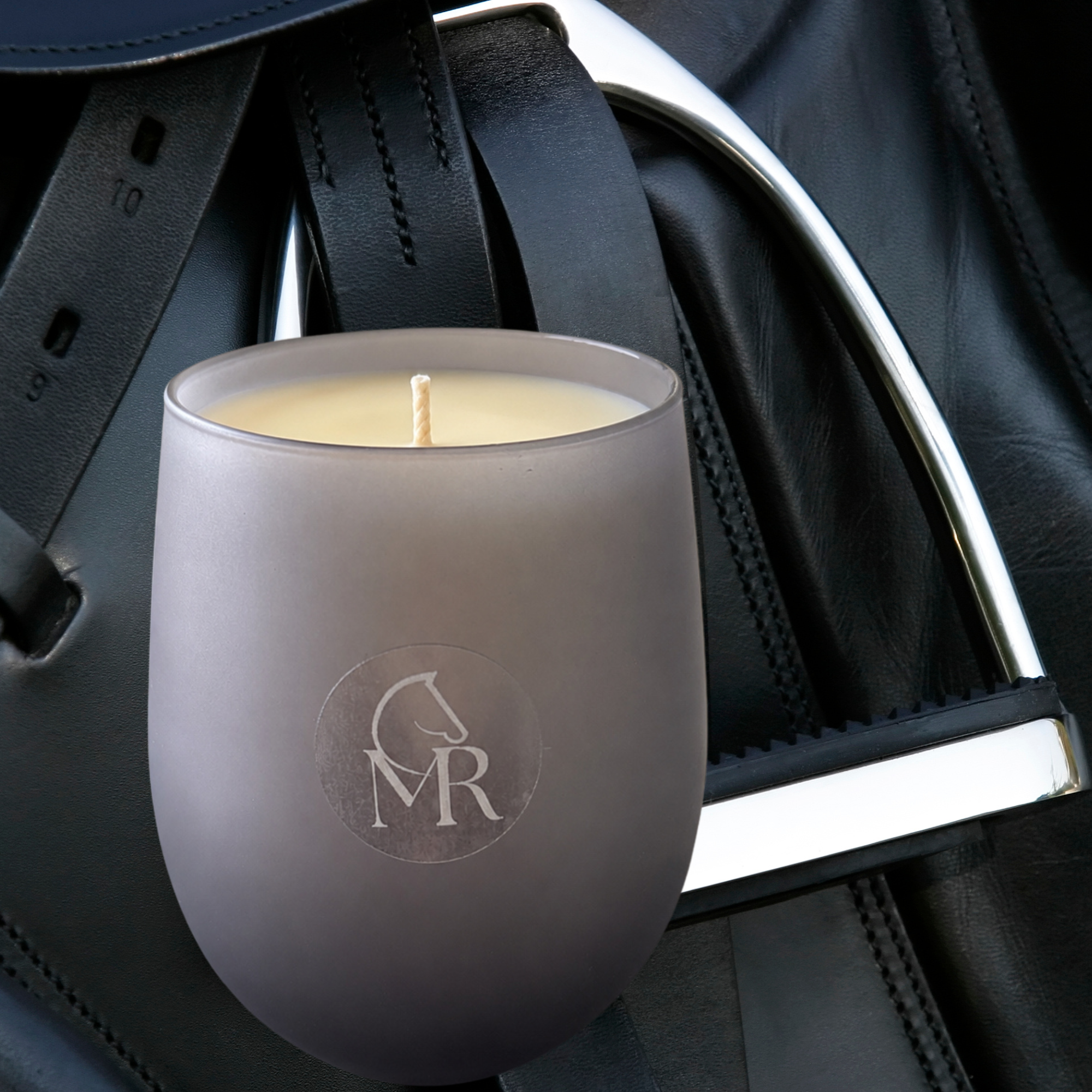 Miss Rio English Pear & Freesia luxury soy candle displayed with equestrian stirrup and leather tack, inspired by Dartmoor heritage.