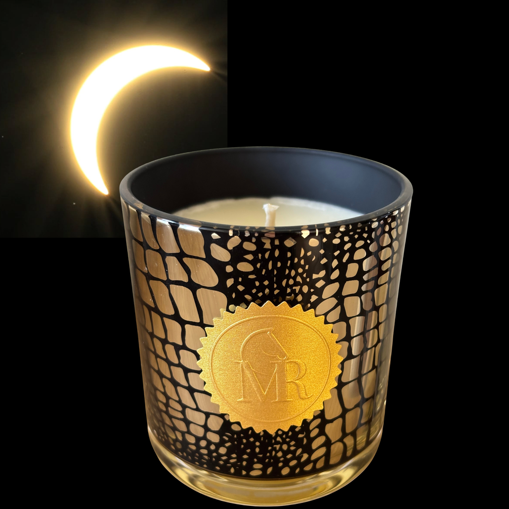 Luxury Miss Rio English Pear & Freesia scented candle in a gold and black glass vessel, featuring a gold Miss Rio seal, photographed beneath a crescent moon.