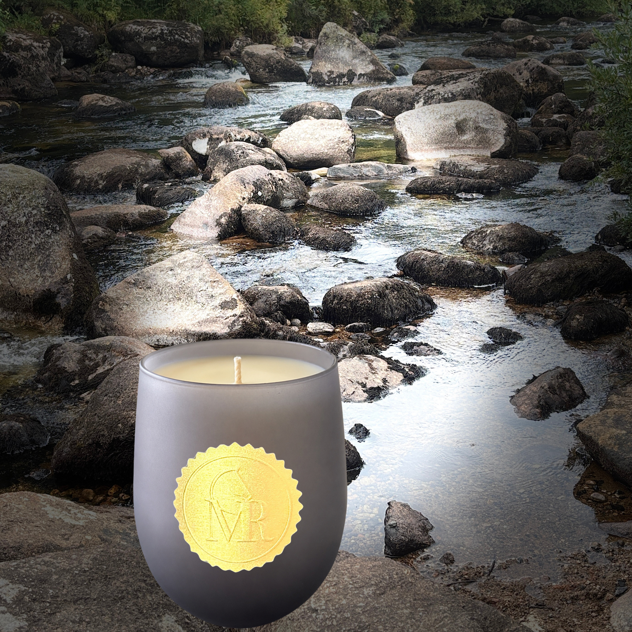 Miss Rio English Pear & Freesia luxury candle photographed beside a flowing Dartmoor river, featuring a dark grey glass vessel and gold MR seal.