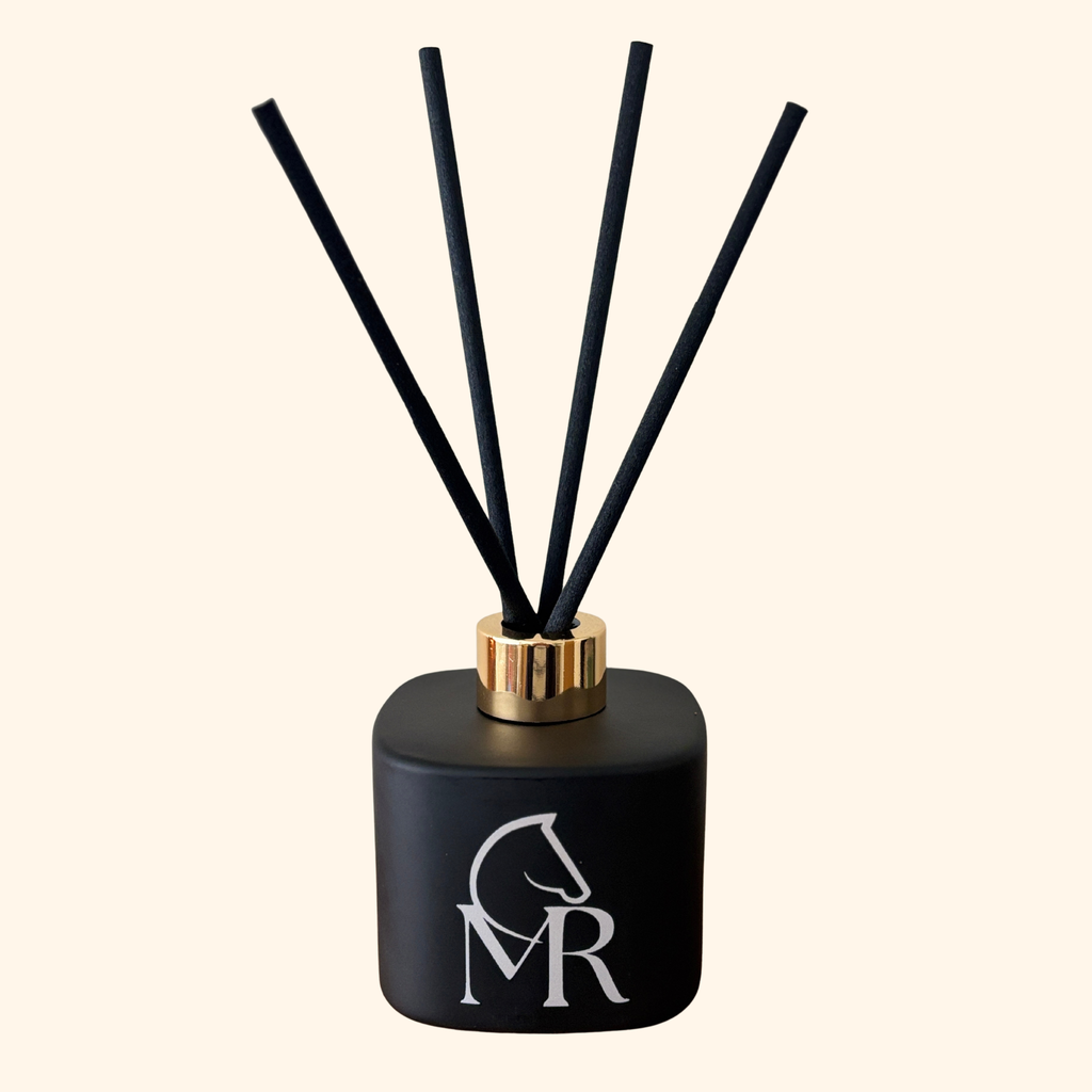 Miss Rio luxury reed diffuser in matte black with gold collar and black reeds on a clean cream background — product studio shot