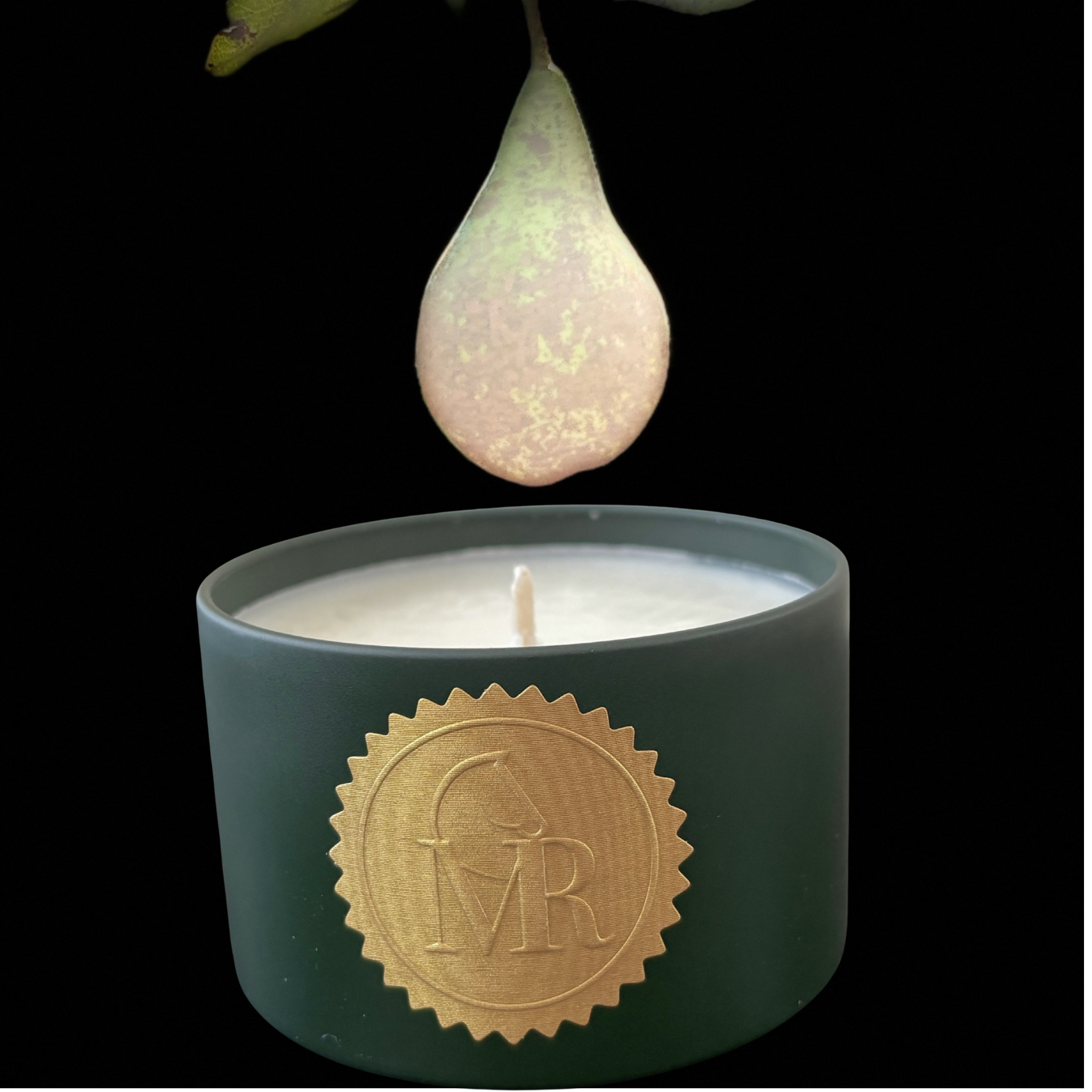 Miss Rio Lucky Penny soy candle in a dark green tin with a gold MR seal, lit with a warm flame against a dramatic black background with a fresh English pear above.